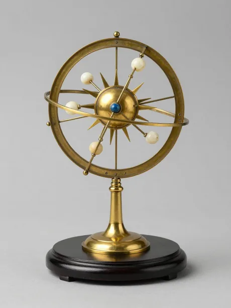 A brass orrery on an ebonised stand, its planetary arms carrying small spheres around a gilt sun