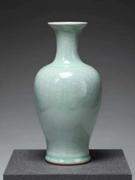 A celadon meiping vase with a high shoulder, its pale sea-green glaze pooling at the foot