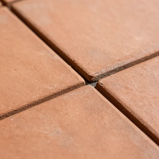 Close-up of handmade terracotta floor tiles, matte uneven clay.