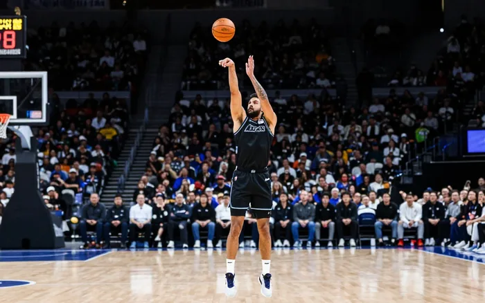 Guard releasing a long three-pointer in a packed arena