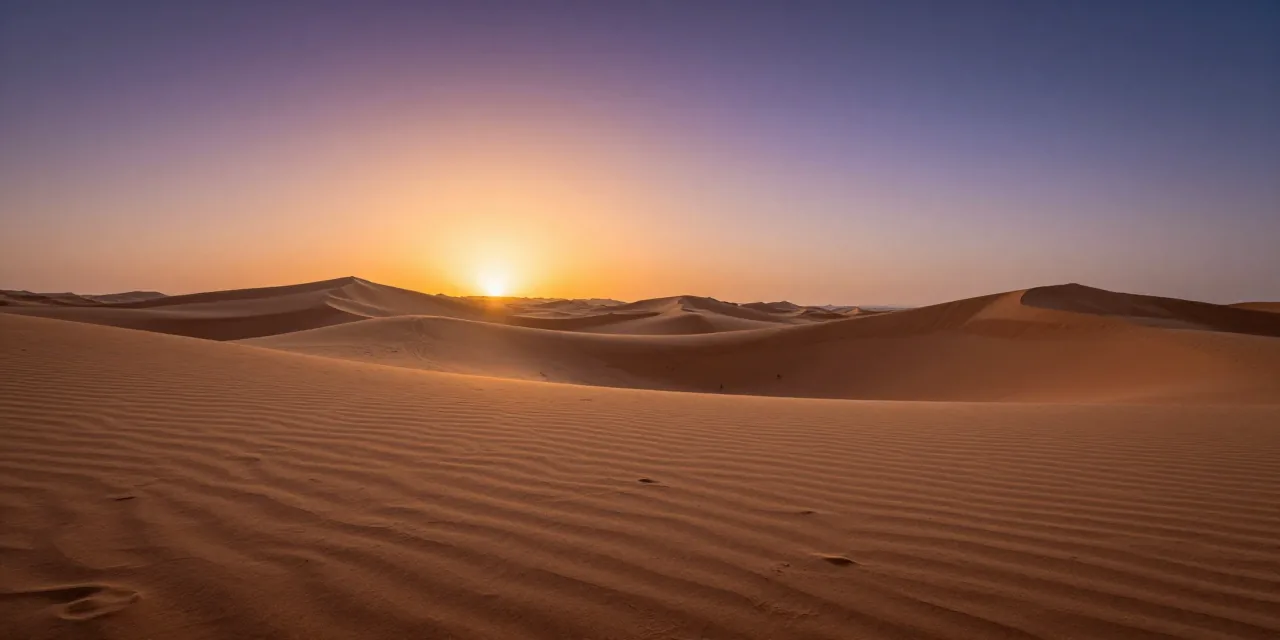 Rippling desert dunes at dusk under a burning orange sky