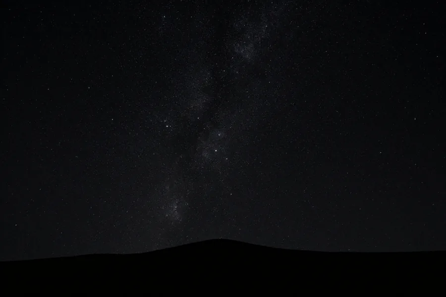 A true-black sky dense with faint stars above a barely readable dark ridge.